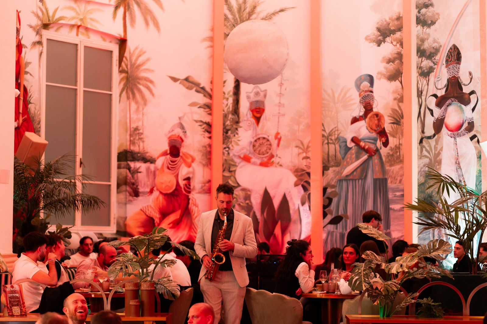 Sassofonista tra i tavoli durante la cena spettacolo REWIND da Temakinho, con i murales alle pareti